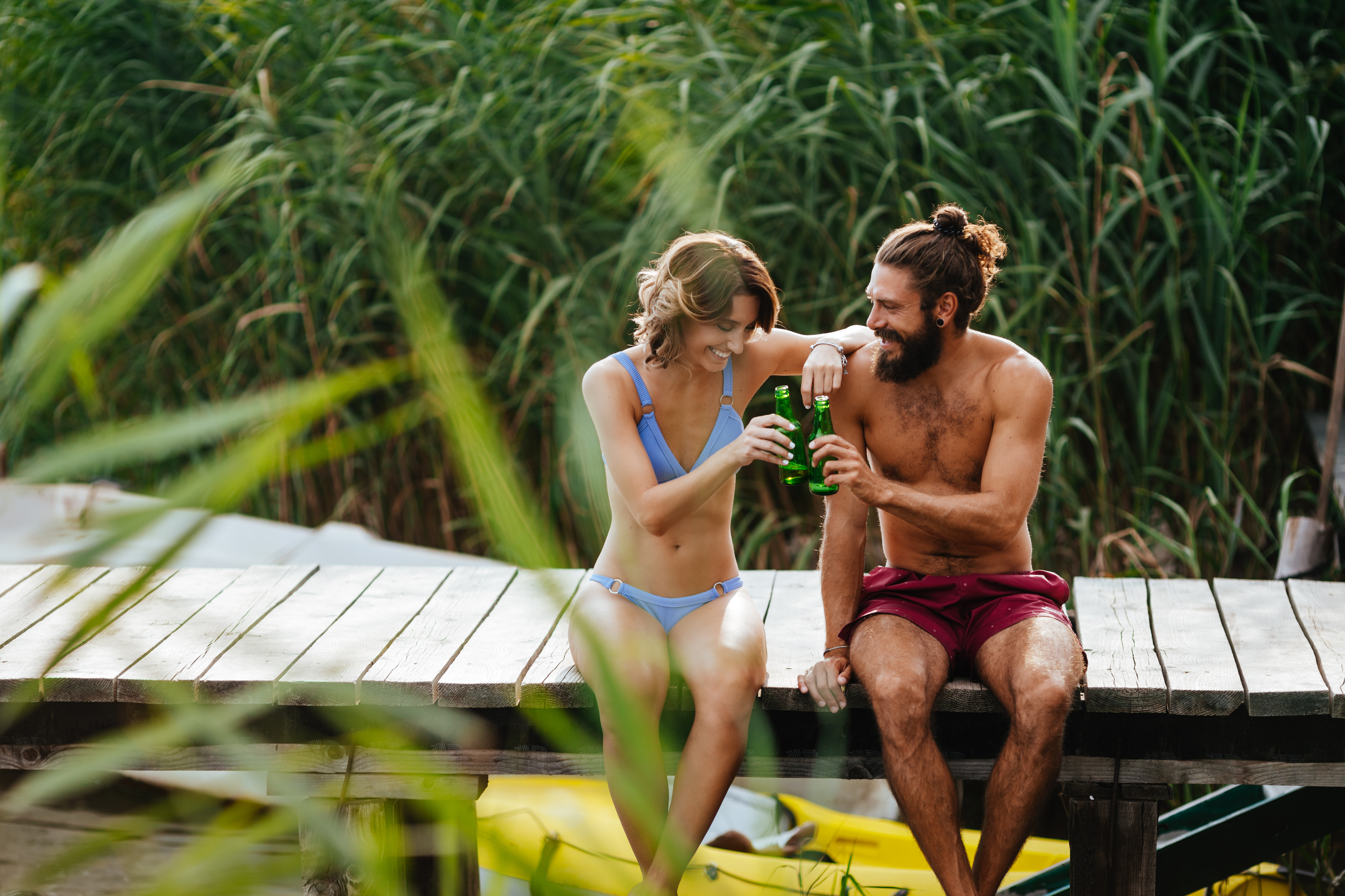 A couple sitting on the dock with a drink